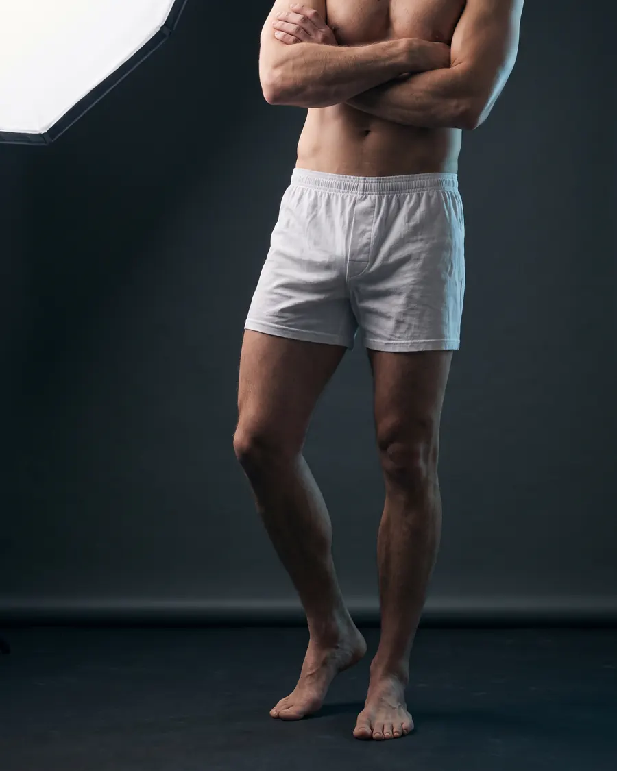 Mann in weißen Boxershorts, Beine in voller Länge, vor dunklem Studiohintergrund