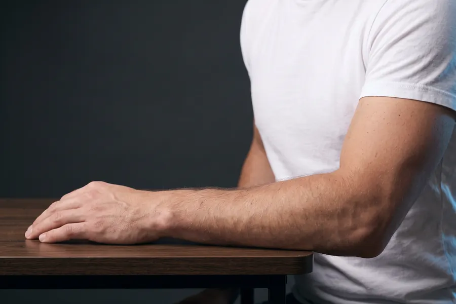 Unterarm und Hand eines Mannes auf dem Oberschenkel