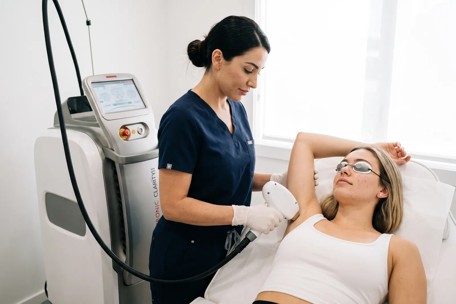 Laser-Expertin behandelt eine Kundin auf der Liege mit dem Lutronic Clarity II