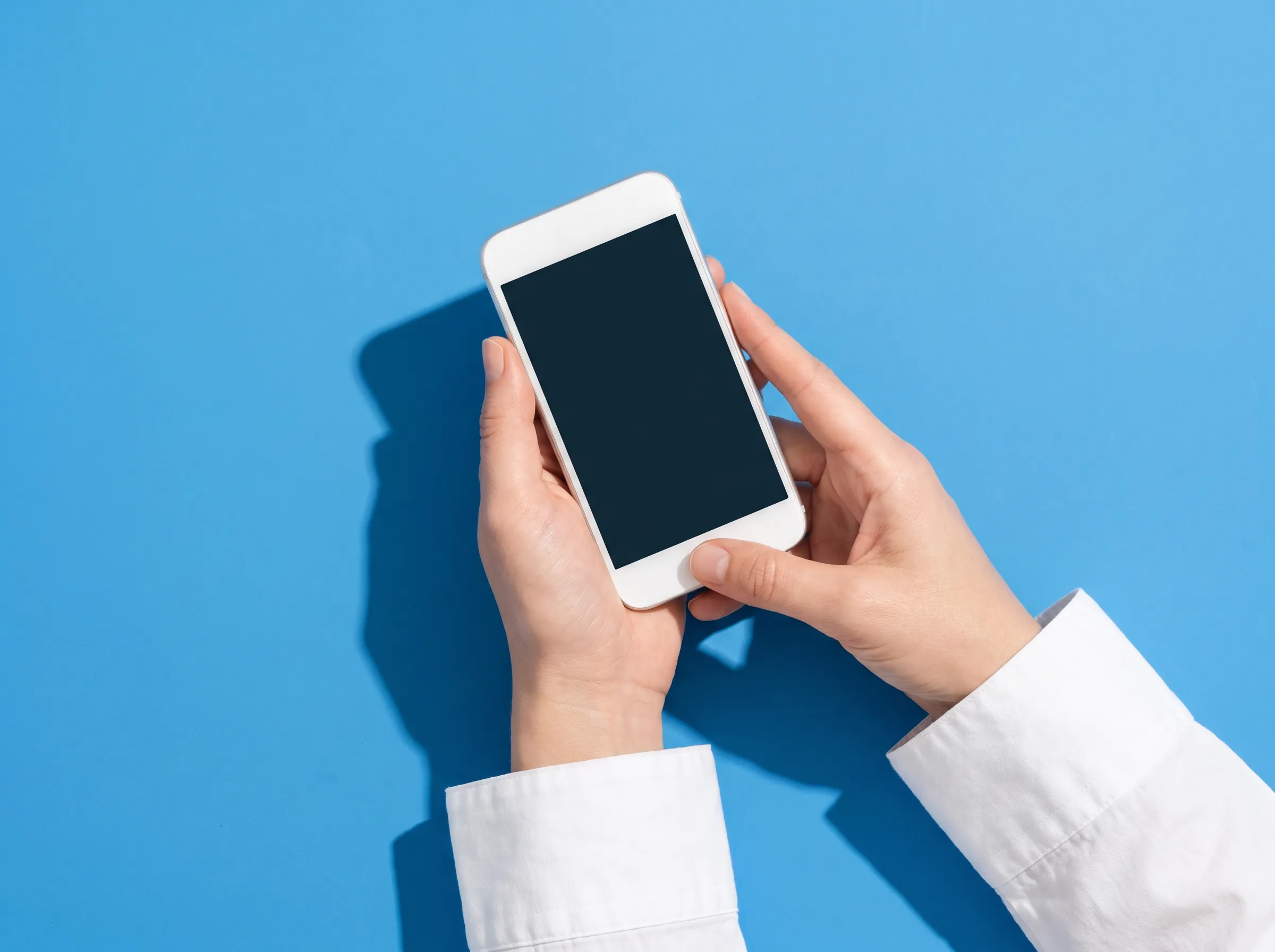 Boş ekranlı bir akıllı telefon tutan eller